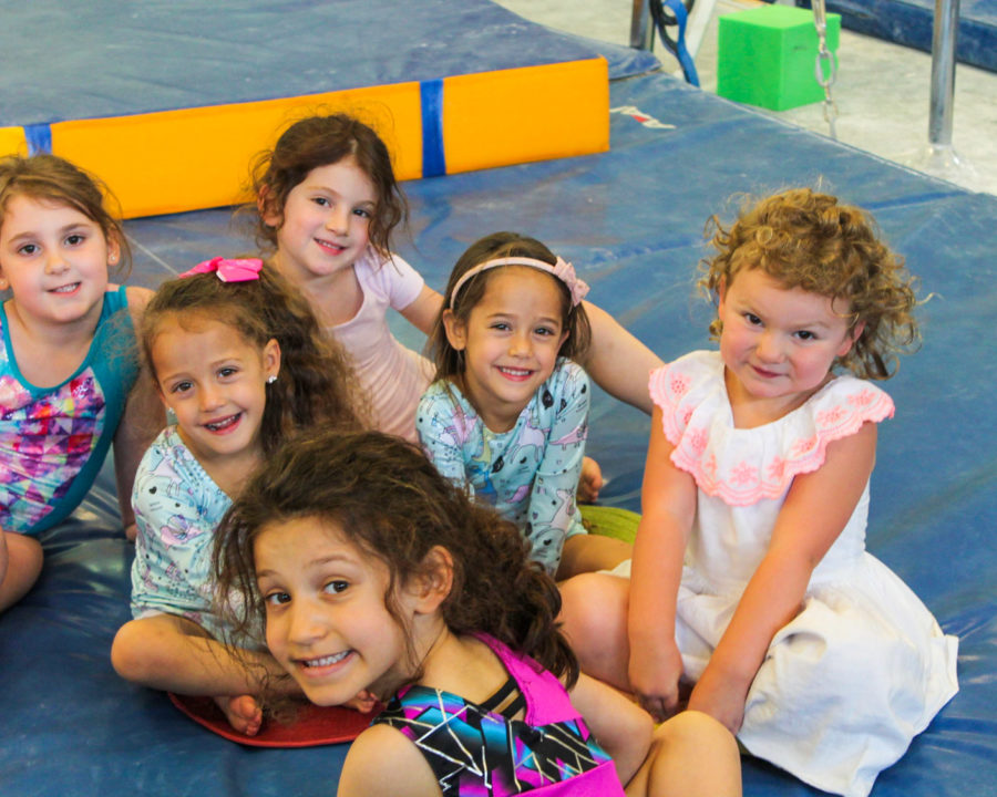 Group of girls sitting on a gymnastics floor mat