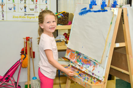 Preschool girl painting on an easel