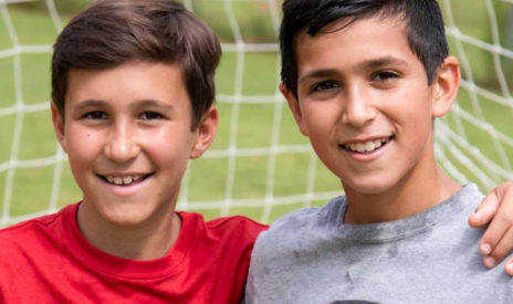 Two boys smiling on the soccer field