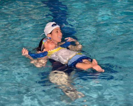 Staff teaching a toddler how to swim