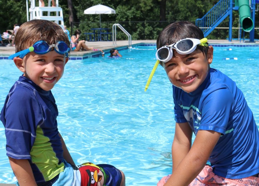 Two boys sitting by a pool smiling