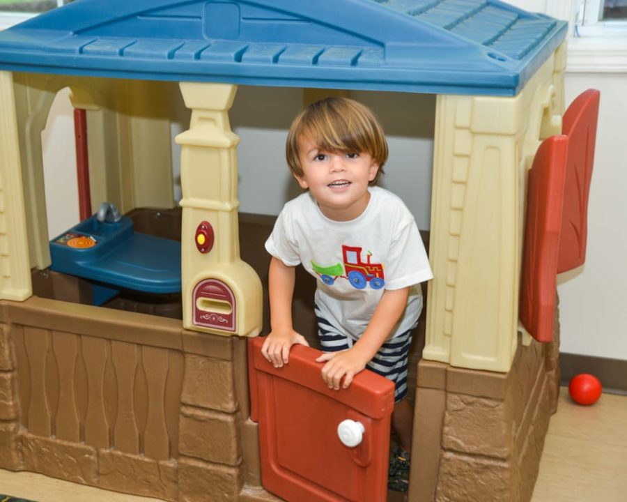 Boy on in a playhouse at the Kid Zone Drop-off Childcare program