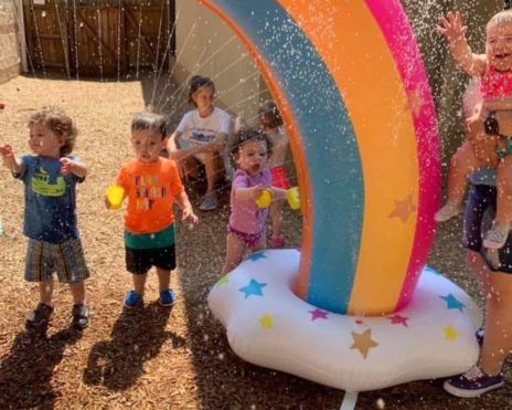 Kids by the rainbow structure at the Sunshine School