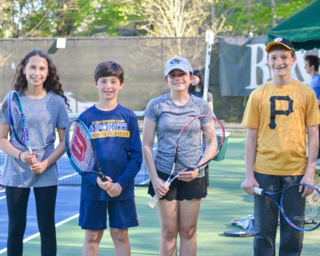 four teens holding tennis rackets