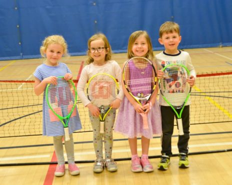 Four kids holding tennis rackets