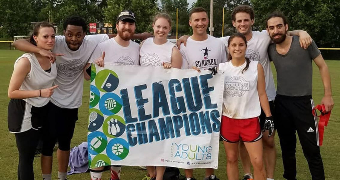 Group of young adults with a League Champions sign